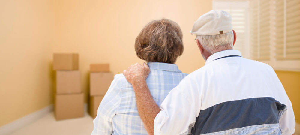 Senior Couple In Room Looking at Moving Boxes on Floor